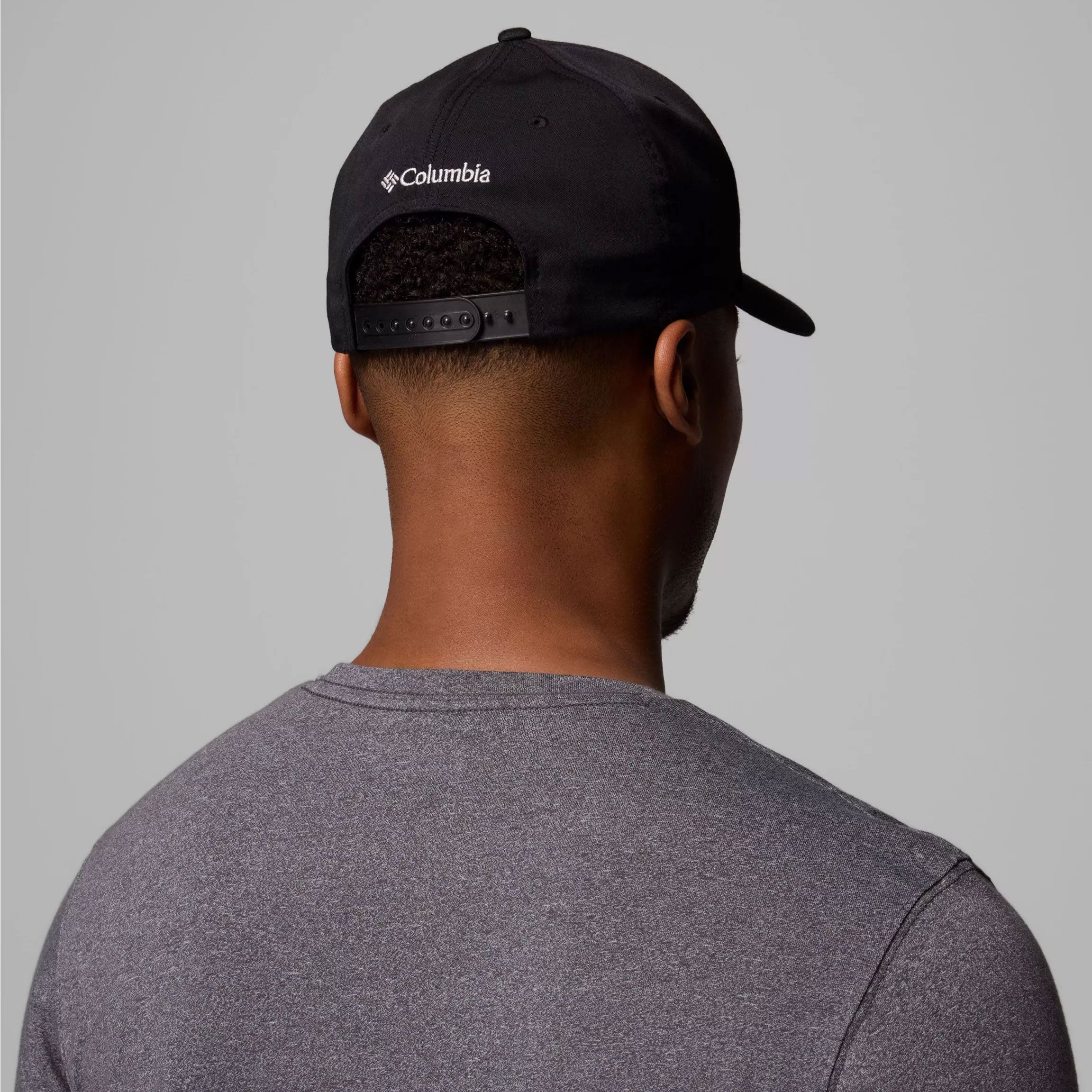 Person wearing a black Columbia cap on a gray background